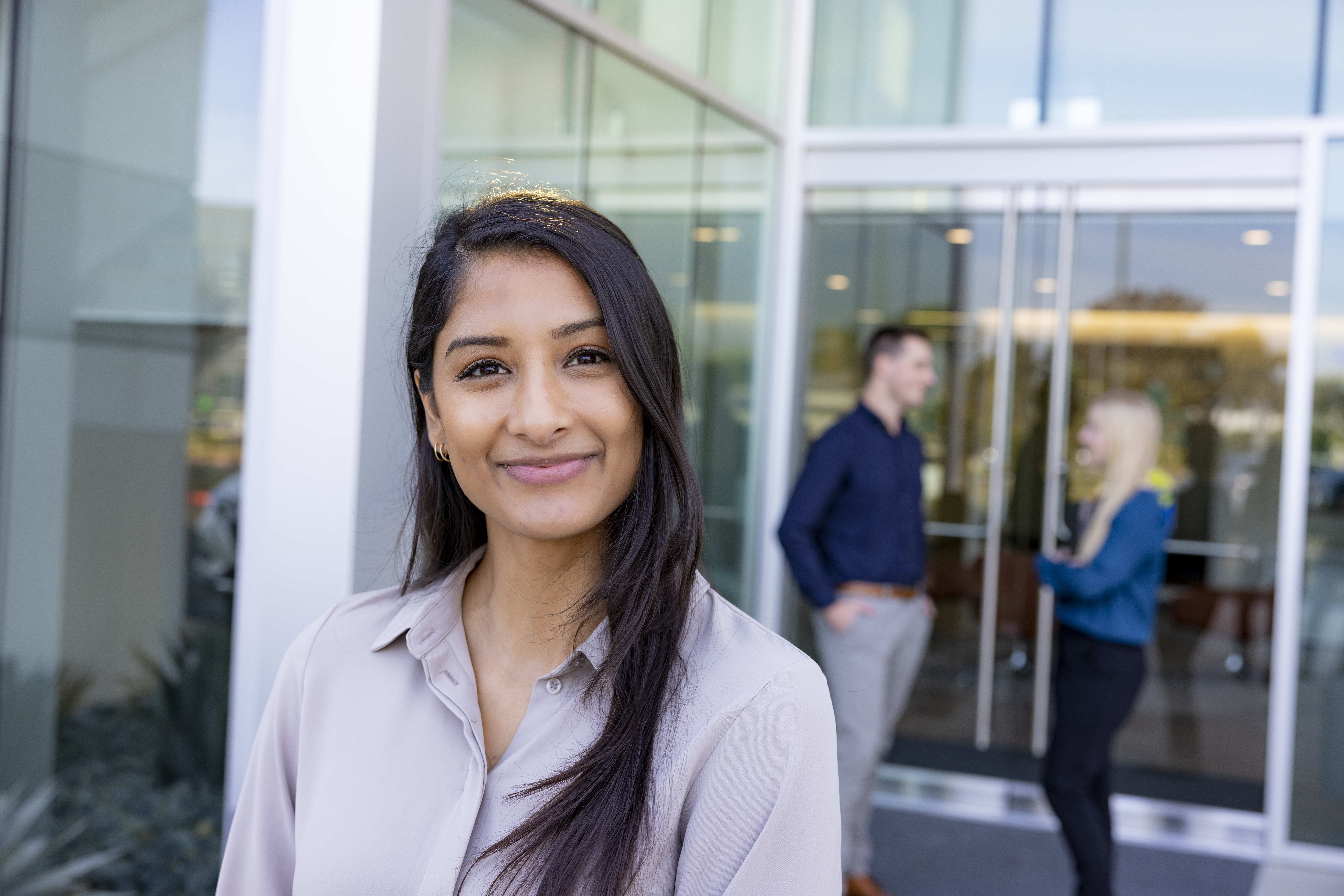 Student looking into the camera while two students are speaking behind her