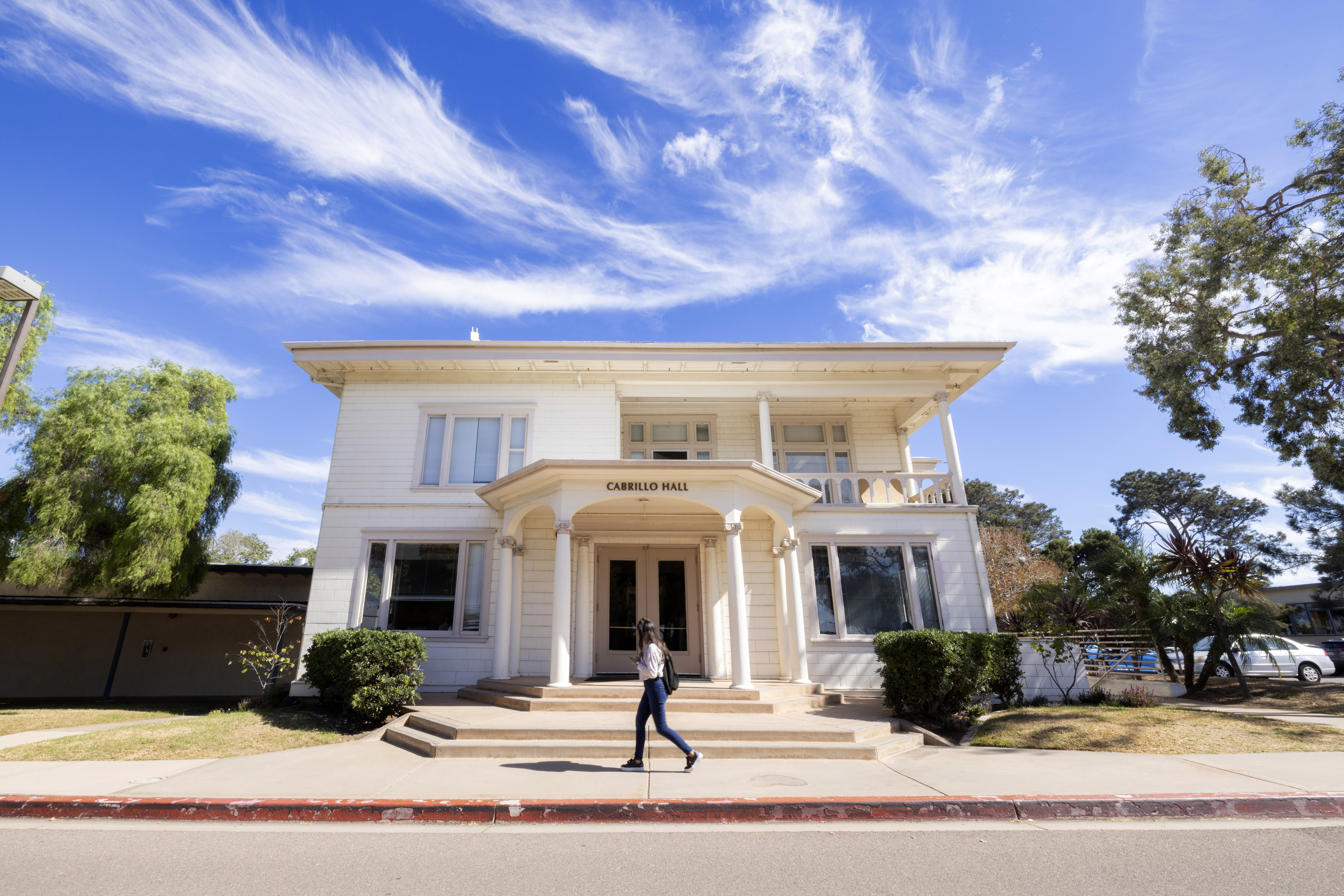 Image of PLNU student walking in front of Cabrillo Hall.
