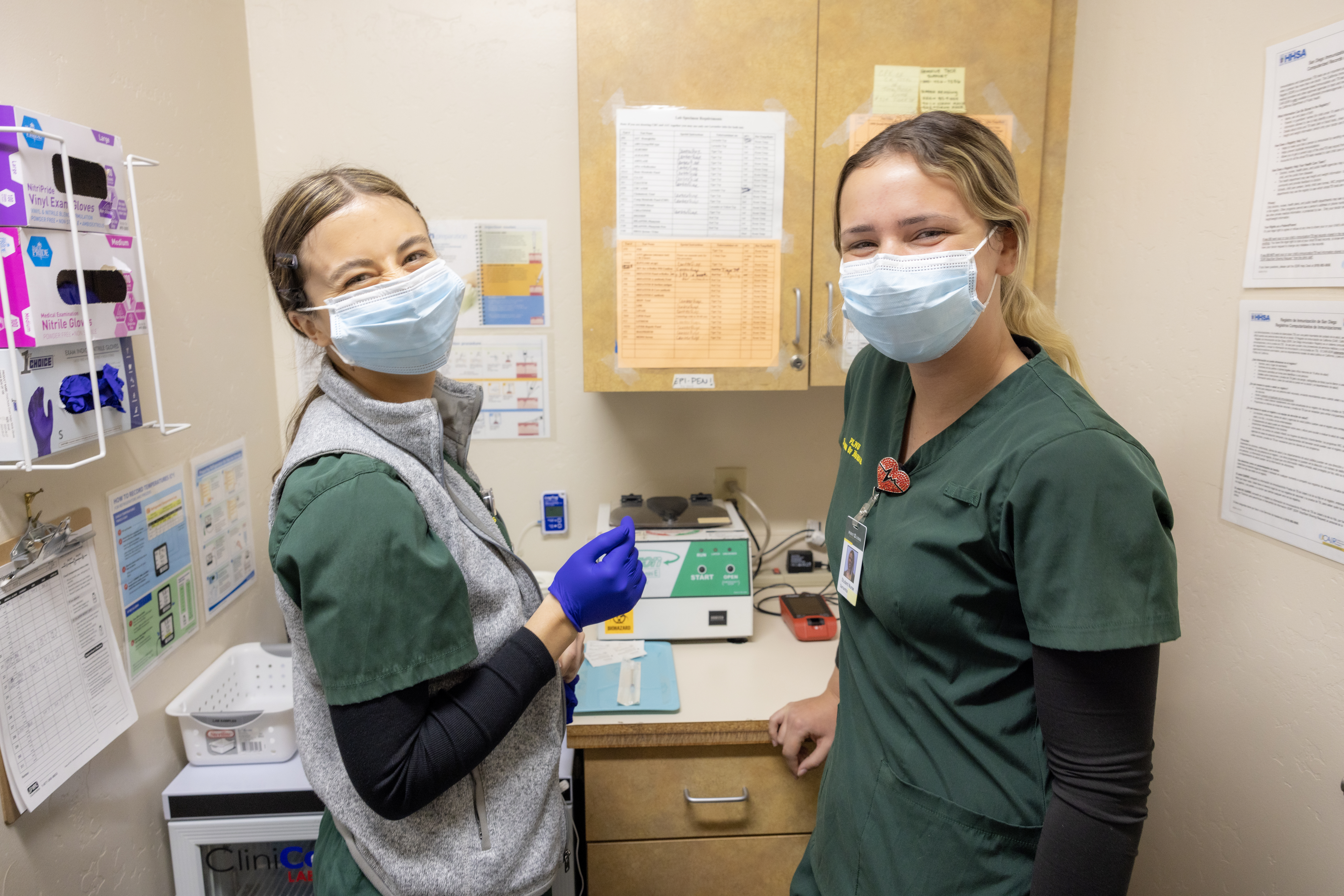 Two HPC PLNU nurses in green smile for a photo while wearing masks