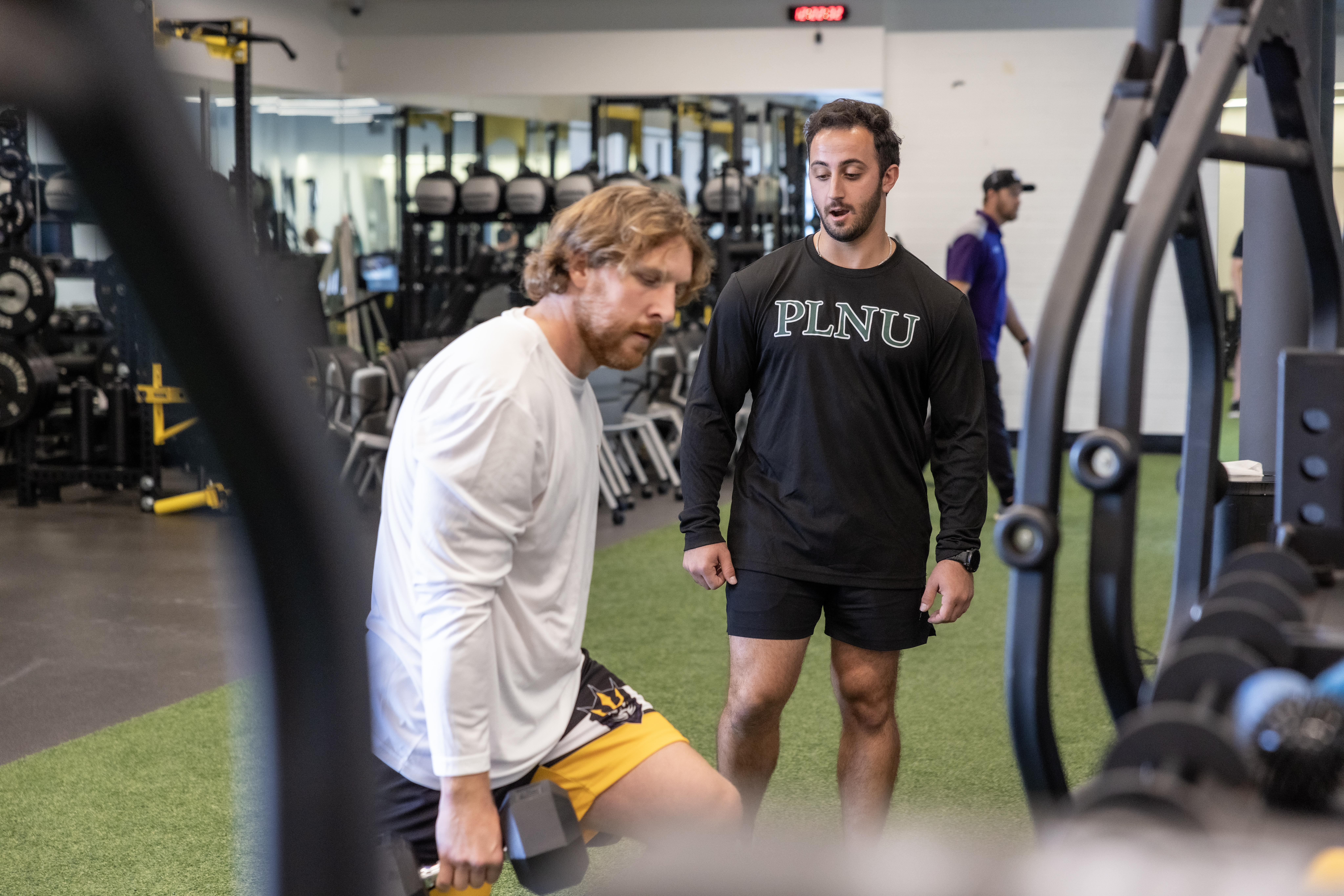 PLNU health coach observes a SD Seals player lifting weights