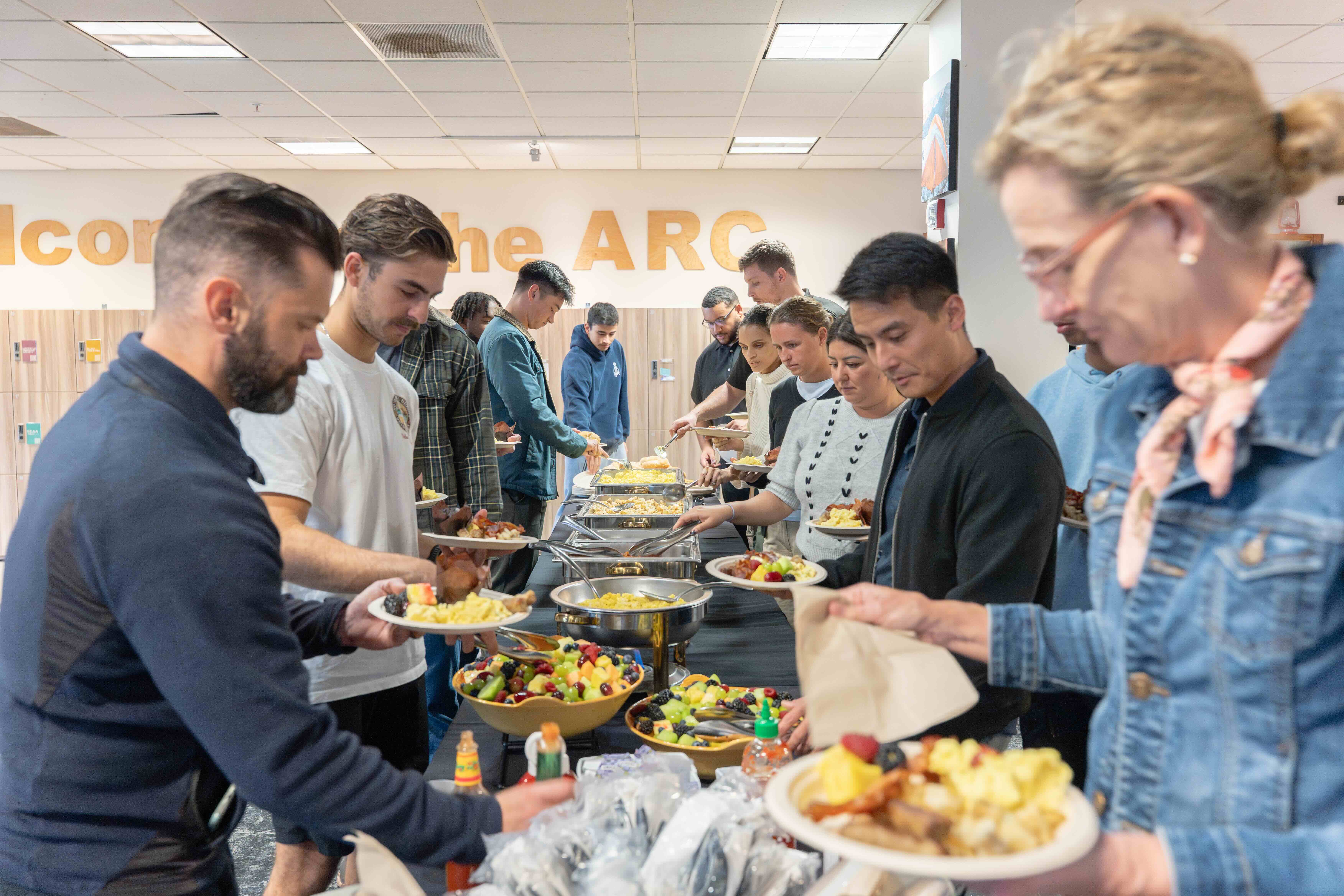 SVA members at the buffet table stacking up plates with food for the 2026 Warrior's Breakfast.