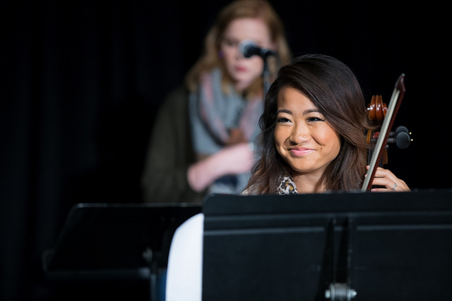 Female student smiles as she pauses during her violin performance