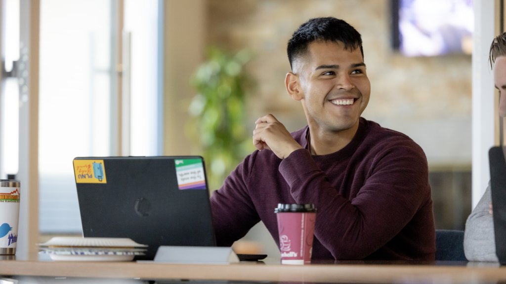 PLNU Student Smiling while Working on Laptop