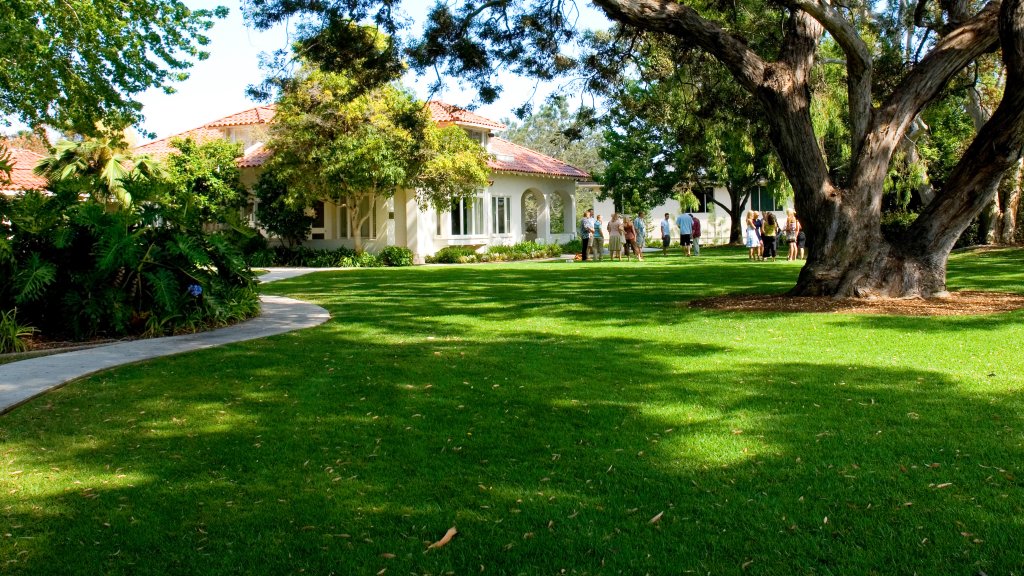 People gather outside on the lawn of the Alumni House
