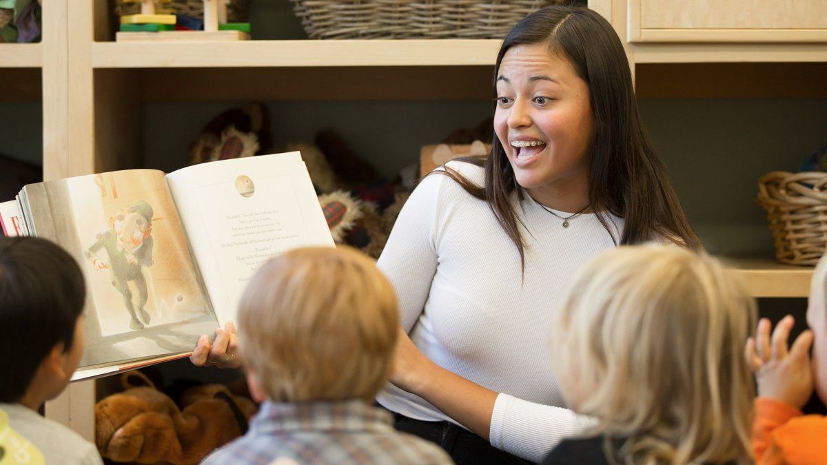 A teacher reads a picture book out loud to a group of small children