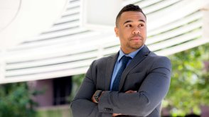 A man in business attire crosses his arms and looks confident