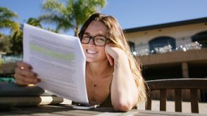 A female PLNU student sits at Sunset Deck studying notes for an upcoming class.