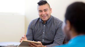 student with a notepad talking to a client