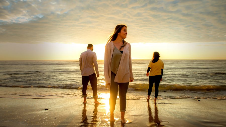 students stand on the beach as the sun sets