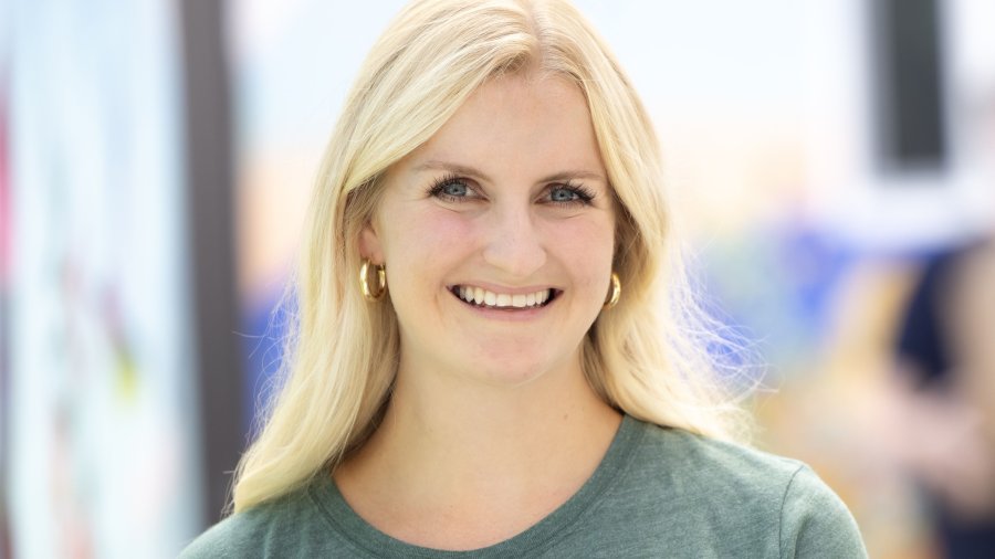 PLNU Master of Science in Nursing (MSN) graduate student Becca Sellner smiles. She is wearing a green PLNU t-shirt.