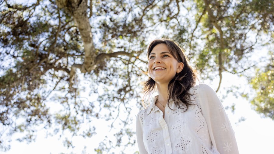 Smiling student standing under tree