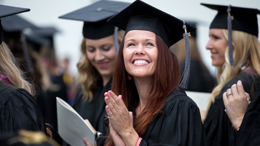 A female PLNU student smiles to the crowd at graduation