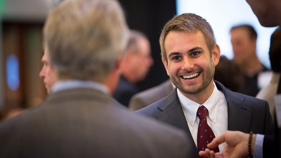 A well-dressed student interacts with a San Diego business professional at a networking event.