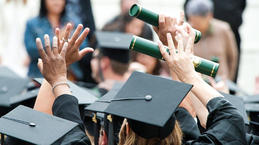 Hands raise in excitement after receiving graduation diplomas