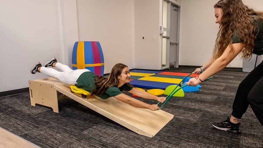 An MSOT student pulls another student down a slide in an classroom training