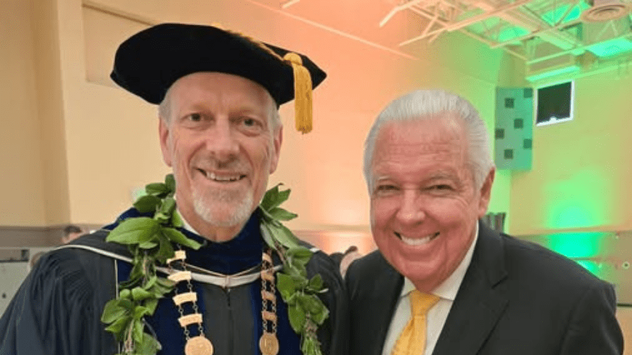 President Kerry Fulcher in presidential regalia posing for picture alongside Alum Barry Meguiar.