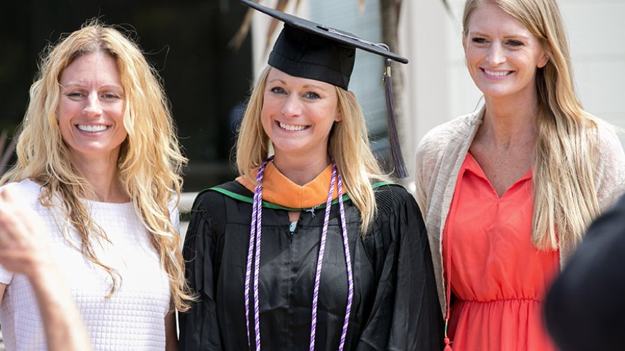 A graduating PLNU student takes a photo with her mom and sister