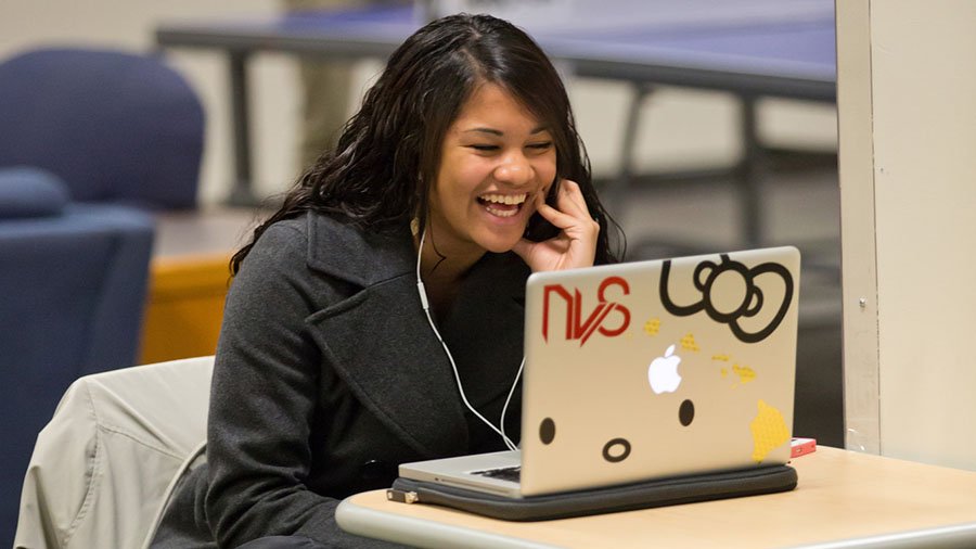 A female student works on her computer in a open space.