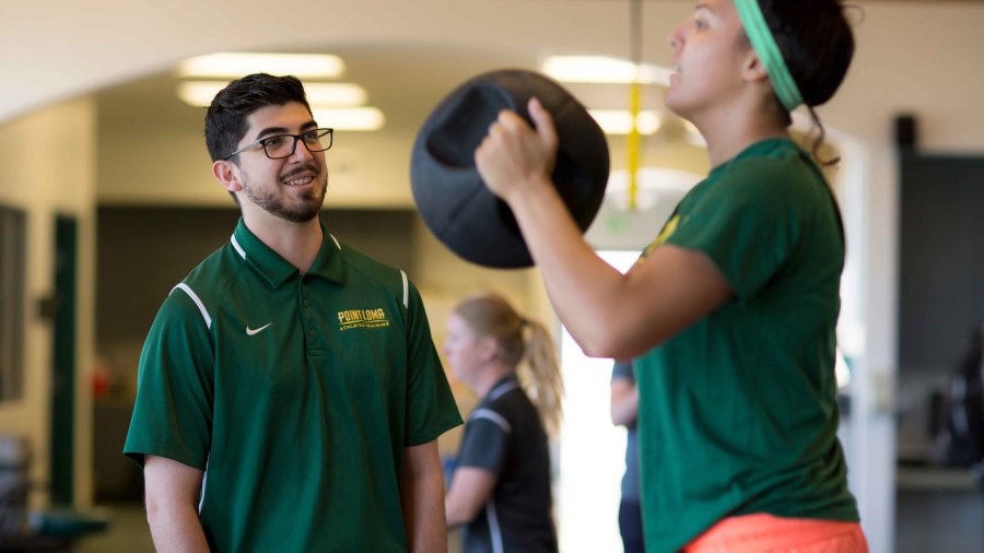 athletic trainer coaching an athlete who is holding a round weight 