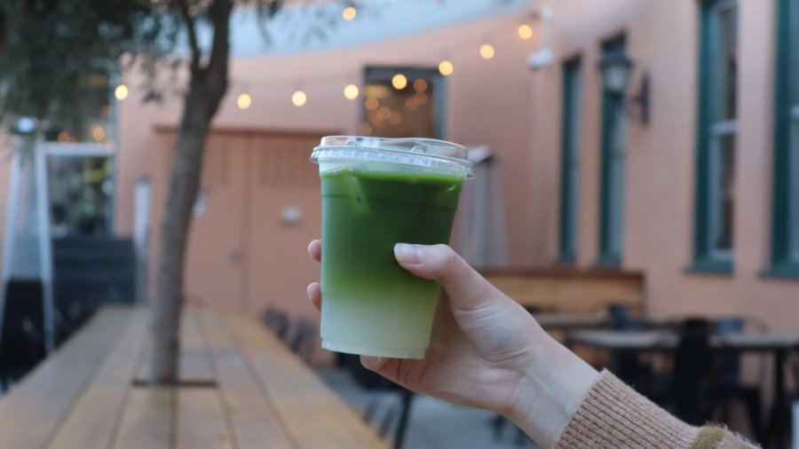 A girl holds up tea at Moniker coffee in San Diego