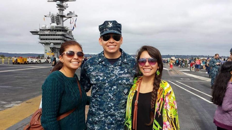 3 people posing a photo. there is a man in the middle wearing a military uniform 