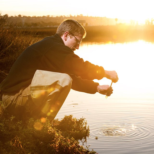 David Cummings collecting water samples at the Tijuana Estuary at sunset