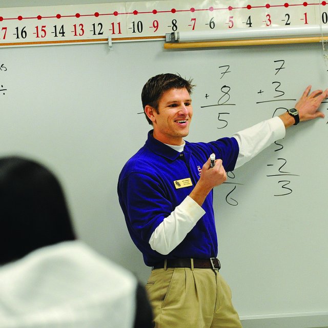 Keith Hubbard explaining subtraction on the whiteboard to his elementary school students 