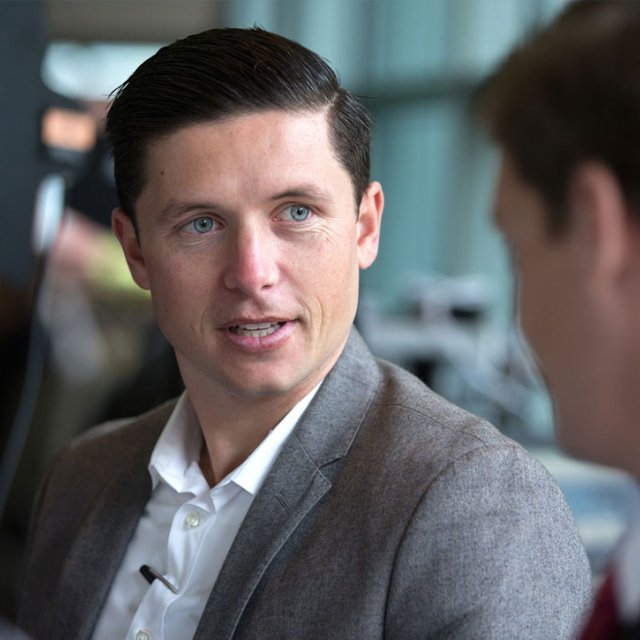 A blue-eyed male student in professional business clothing networks at a business development event