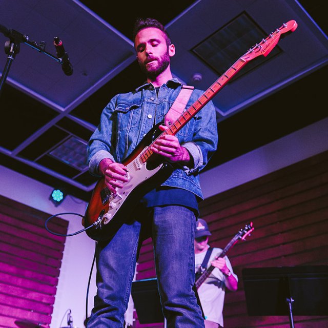 PLNU student Ian plays his guitar at a Musoffee night in the ARC.