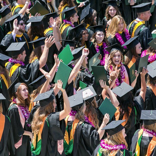 PLNU students in cap and gown celebrate receiving their diplomas during commencement