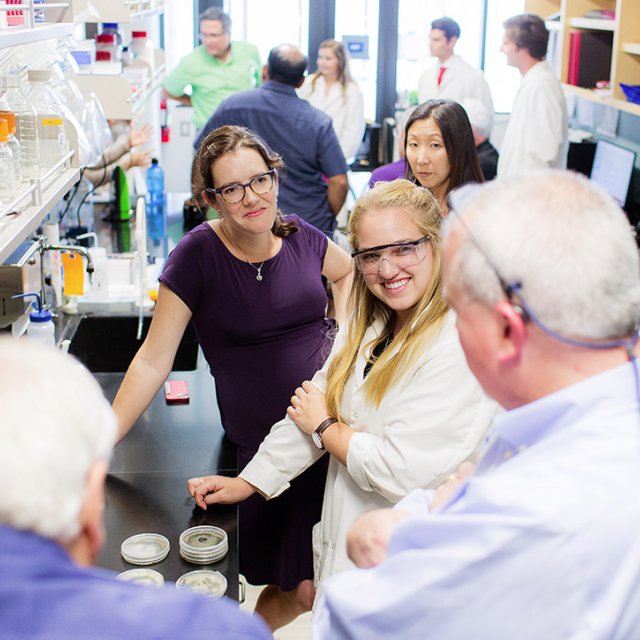 A PLNU science student shows and explains an experiment she is working on to visiting alumni.