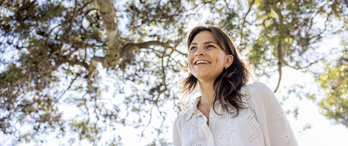 Smiling student standing under tree