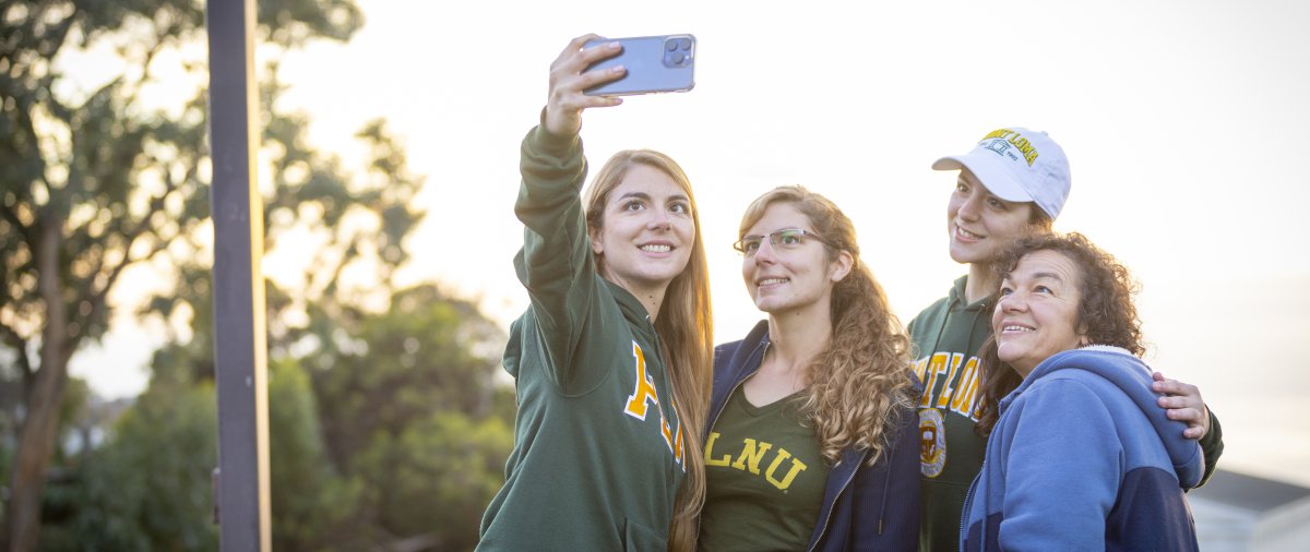 PLNU student taking selfie with her family in front of the Greek