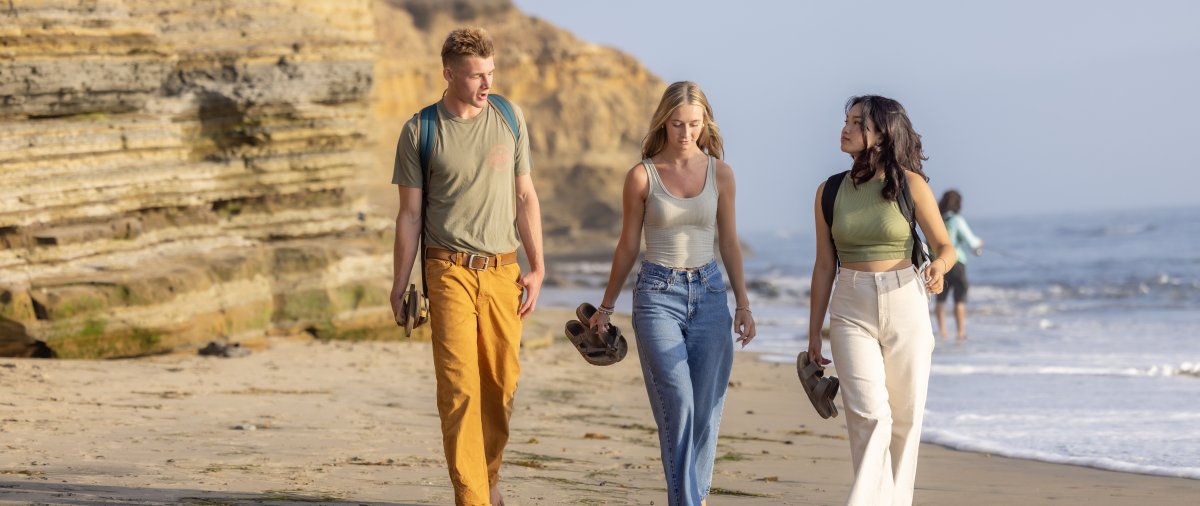 3 students chatting while walking on the beach