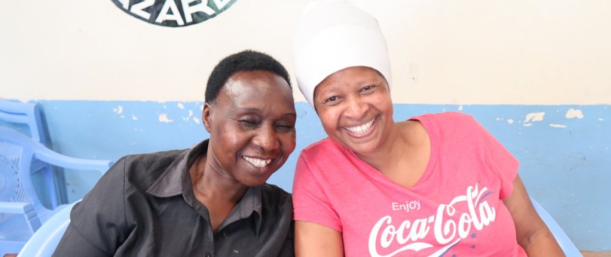 Two Kenyan women sit and smile in a church