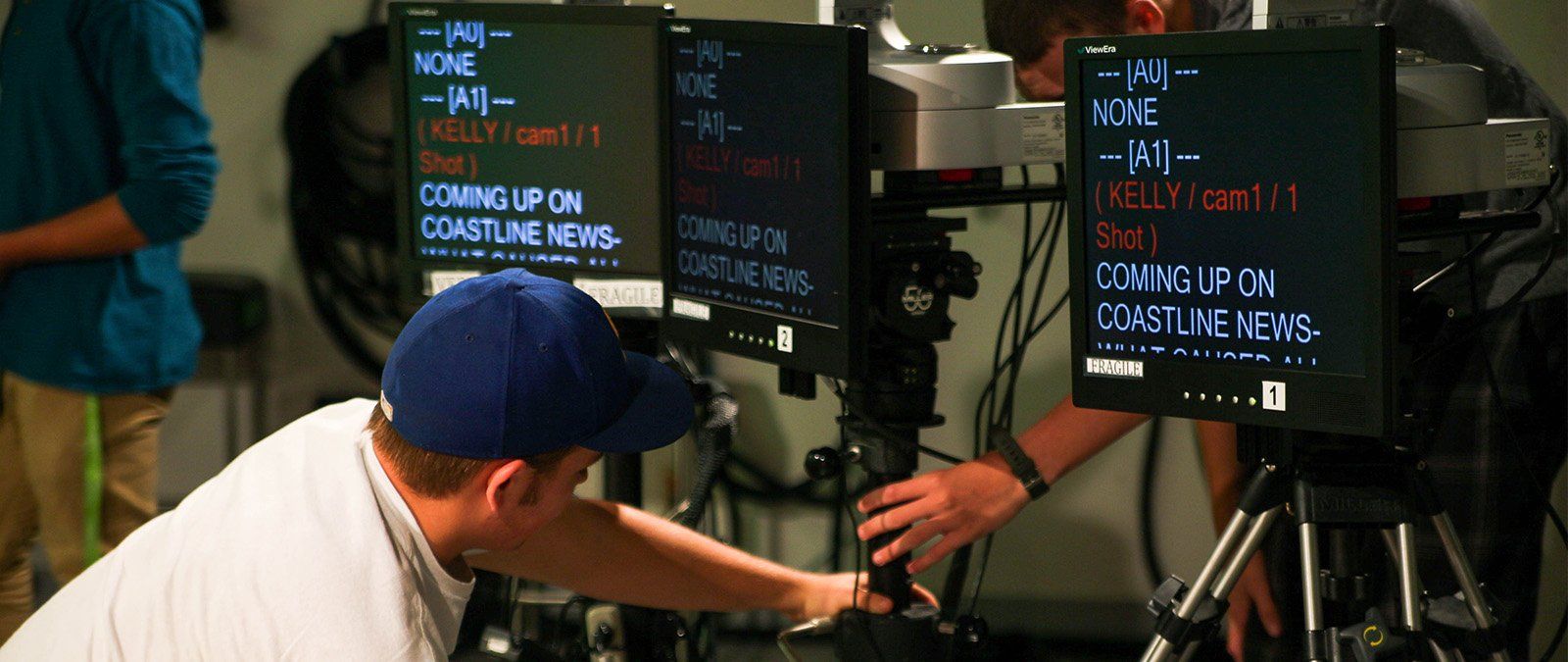 A male student sets up a camera and screen for the anchors to use during a Point TV recording.