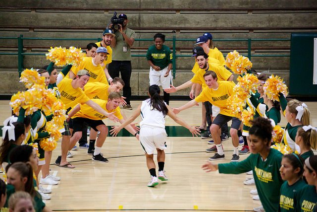 A women's basketball player runs through a tunnel of fans