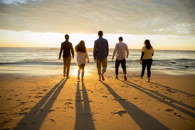 People walk towards the ocean and sunset