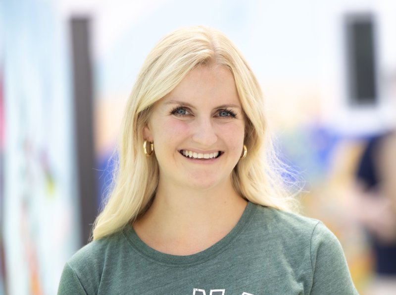 PLNU Master of Science in Nursing (MSN) graduate student Becca Sellner smiles. She is wearing a green PLNU t-shirt.