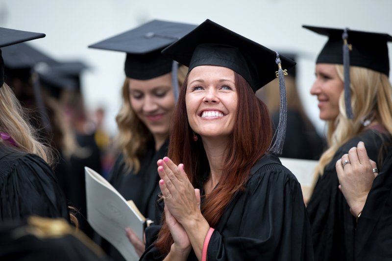 A female PLNU student smiles to the crowd at graduation