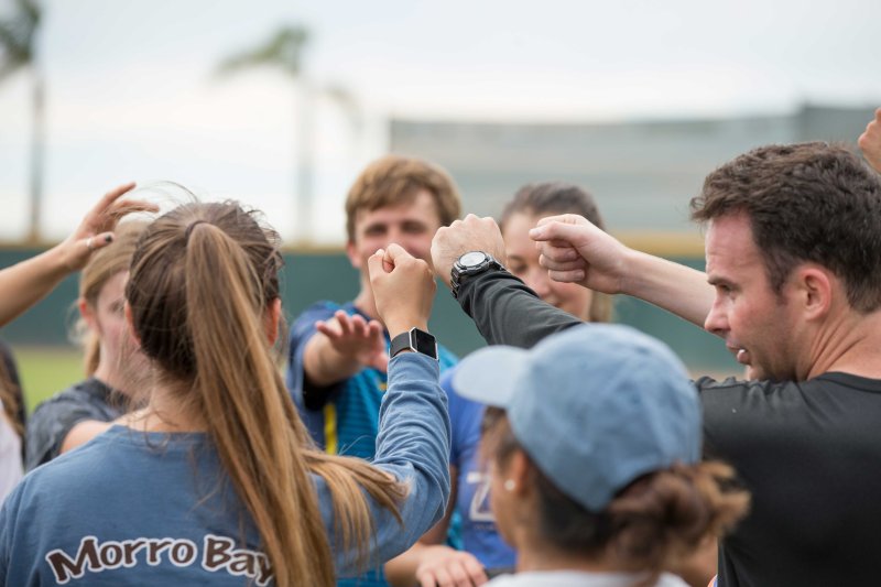 A coach huddles up with his players for a high five