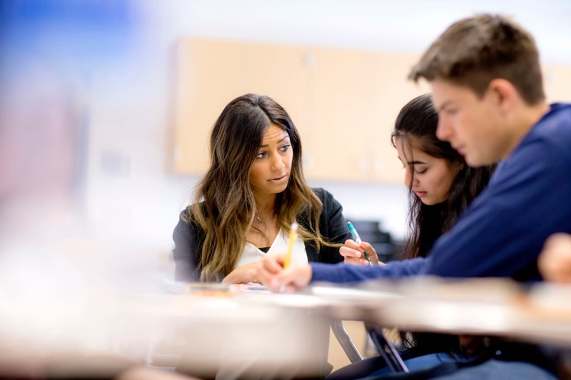 A high school teacher helps a student with her assignment.