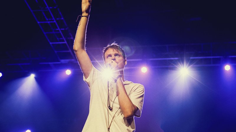 Jason David Slutyer raises his hands in praise as he performs his song on stage.