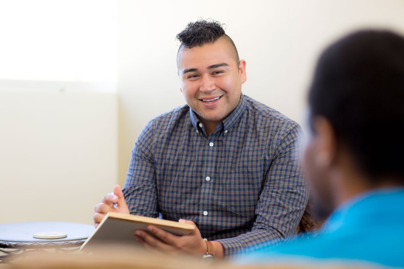 student with a notepad talking to a client