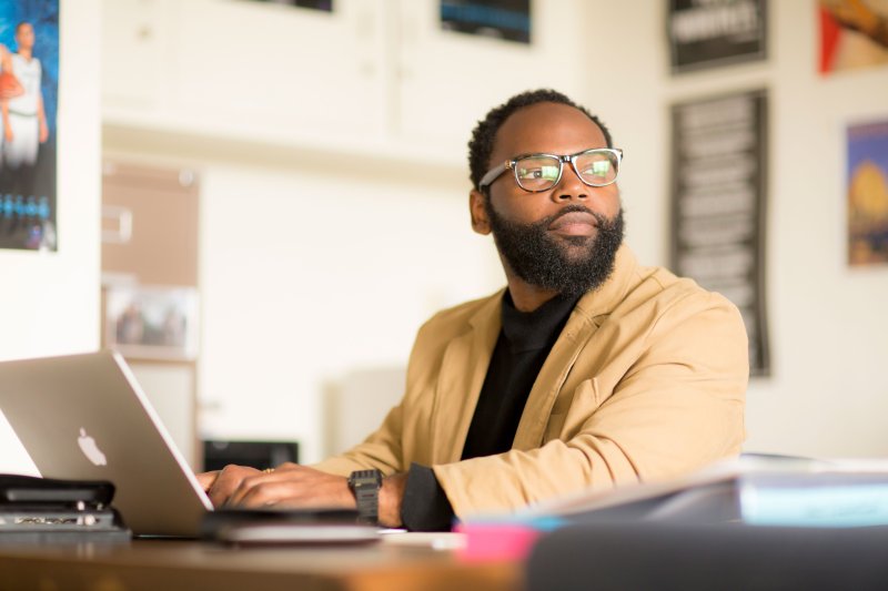 student with laptop looking into the distance 