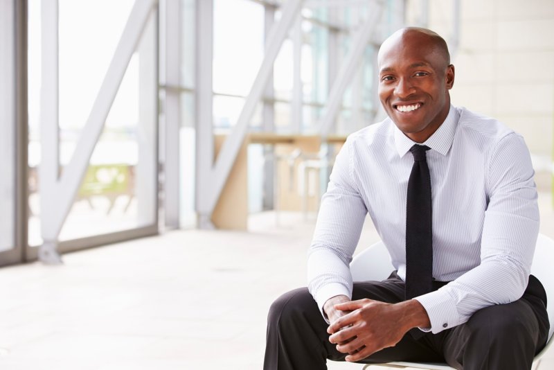 Admitting mistakes is an important part of leadership, pictured is a man sitting down, dressed nicely, and smiling. 