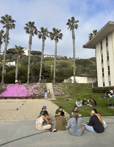 A group of PLNU students sit outside of Young Residence Hall at the 2023 Lights Out event. 